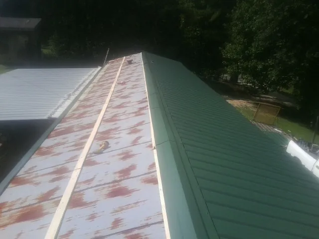 Old rusted panels beside newly installed green metal roofing — Wind Damage Roof Repair by Roofing Brothers in Strasburg